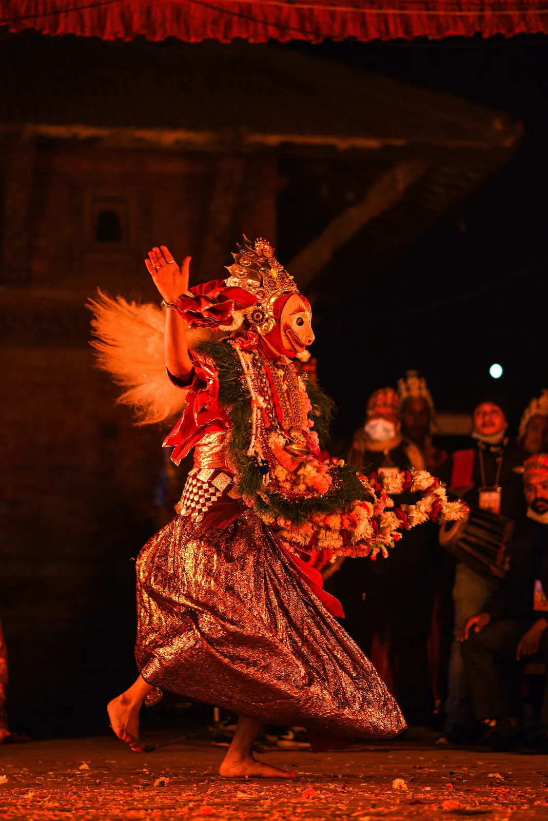 A masked dancer in red spins, his costume flaring out